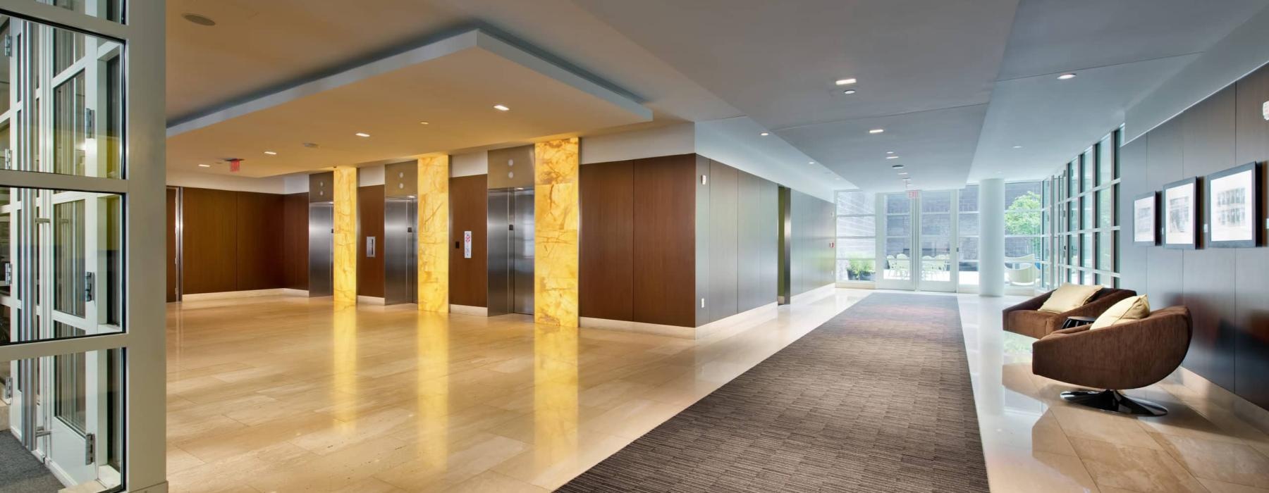 Resident lounge and lobby at our apartments for rent in Washington DC, featuring wood grain flooring and cushioned chairs.